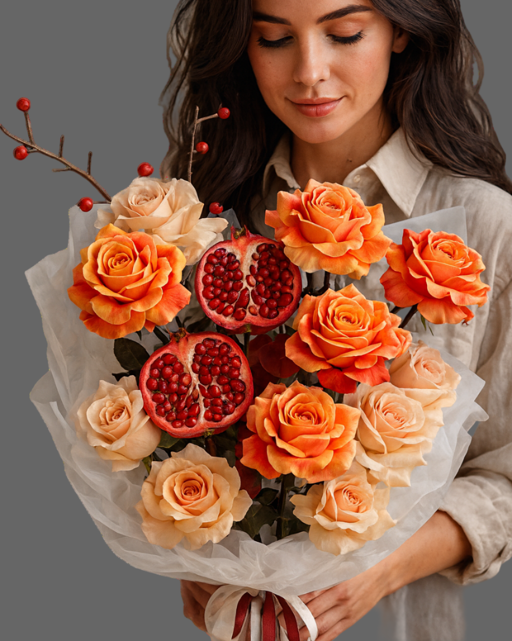 A luxury bouquet with orange roses edged in red, cream roses, and fresh cut pomegranates, styled in soft layered wrapping with burgundy and white ribbons. Premium autumn design.