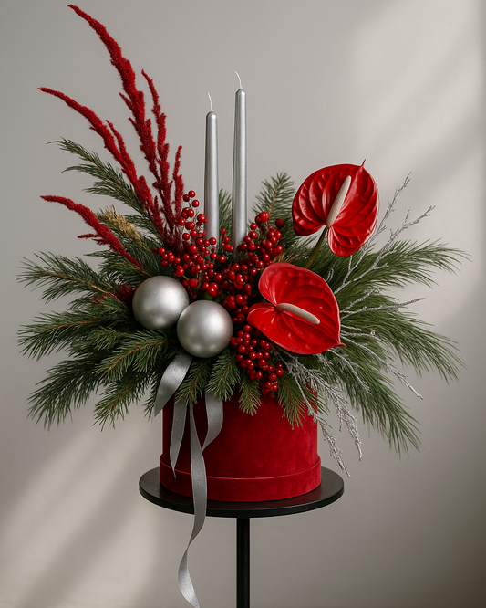 Luxury red holiday centerpiece with natural greenery, candles and festive accents in a studio setting.
