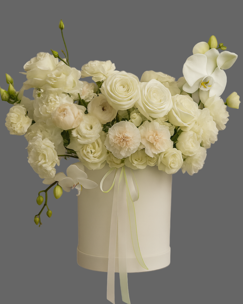Elegant white flower arrangement in a luxury hat box with orchids and delicate roses, perfect for weddings or premium gifts.
