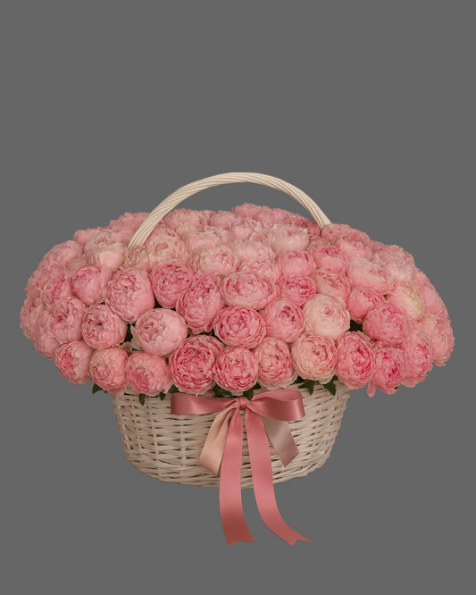 Luxury white basket filled with 100 pink peonies on a gray background. Exclusive premium floral arrangement for weddings, anniversaries, and romantic occasions in Miami.