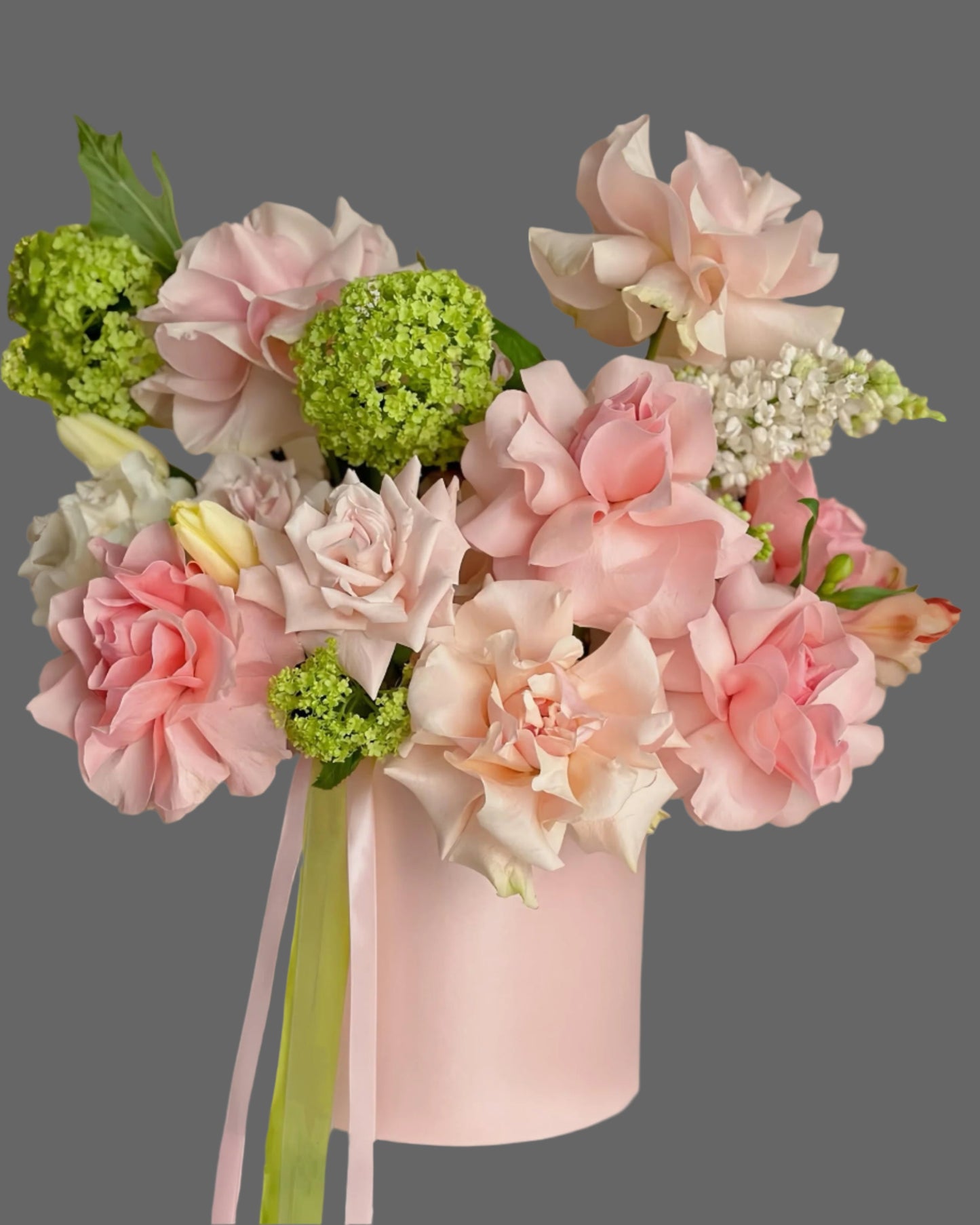 Tender pink and green flower arrangement in a round hat box, decorated with ribbons. Elegant gift for birthdays, anniversaries, Mother’s Day, or baby showers. Available in multiple sizes with flower delivery in Miami and nearby areas.